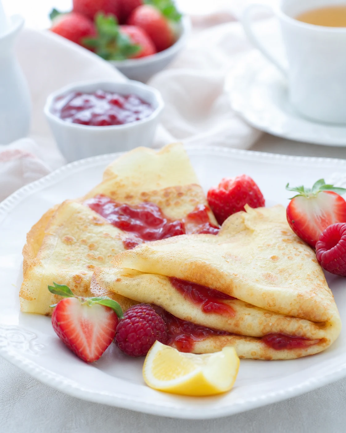Crêpes sans gluten pliées et servies avec confiture, citron et fruits rouges