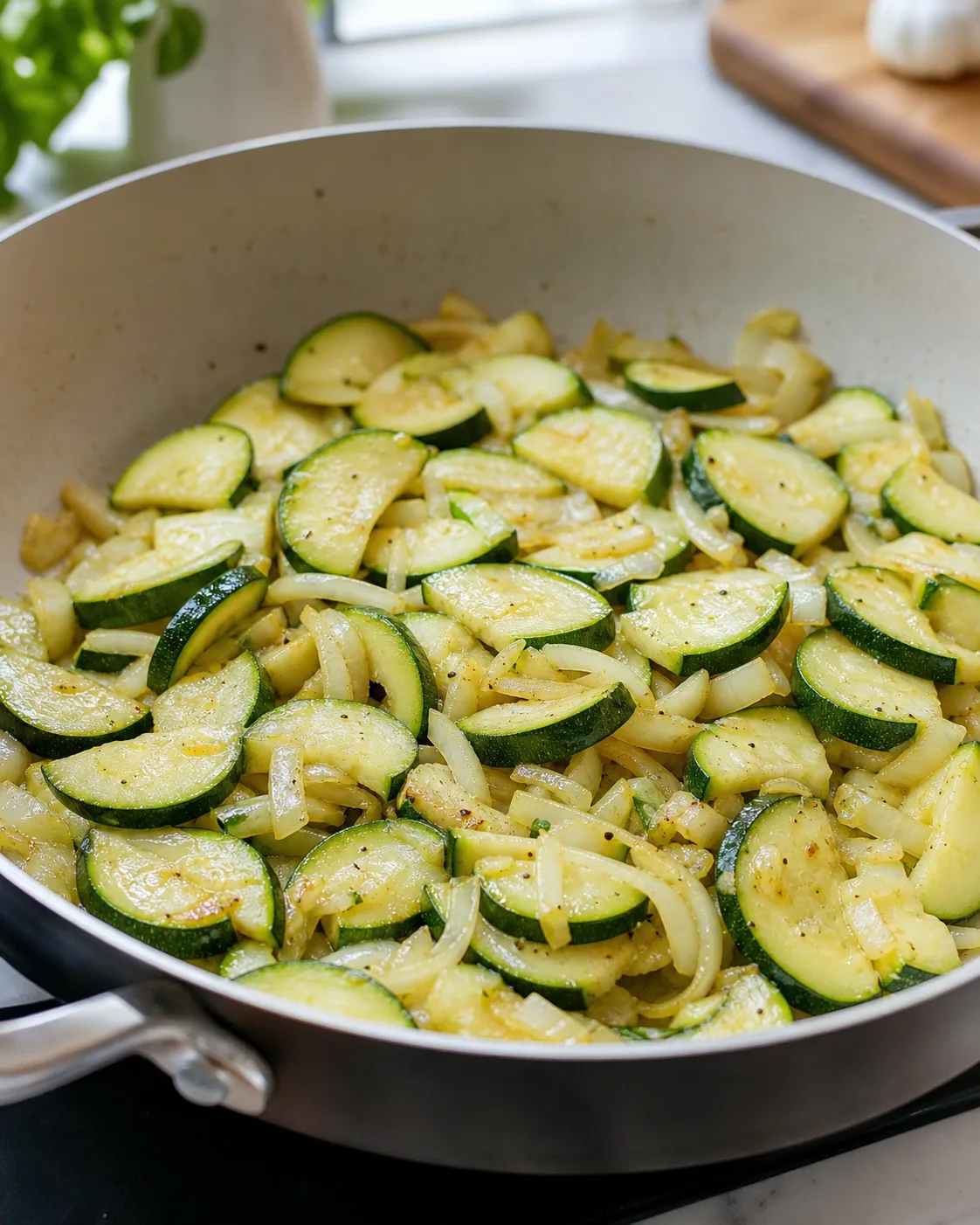 Courgettes et oignon en cuisson dans une grande sauteuse avant le montage du gratin
