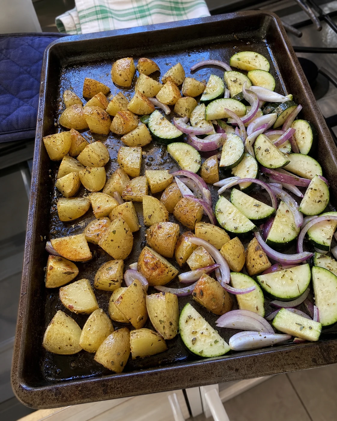 Plaque de cuisson avec pommes de terre pre-roties et courgettes ajoutees pour la deuxieme partie de cuisson